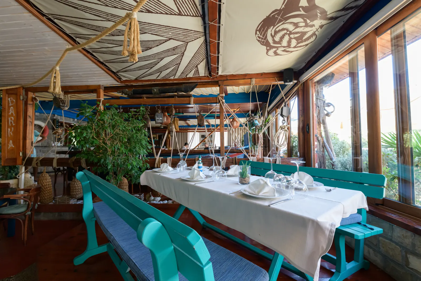 A set table by the window with turquoise benches